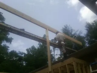 Carpenter setting a ridge beam over a new addition frame — Ice Dam Removal by Roofing Brothers in Gates Mills