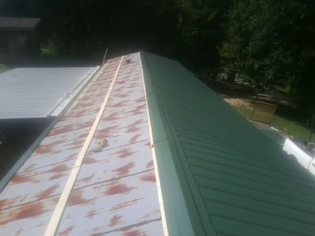 Old rusted panels beside newly installed green metal roofing — Wind Damage Roof Repair by Roofing Brothers in Gates Mills