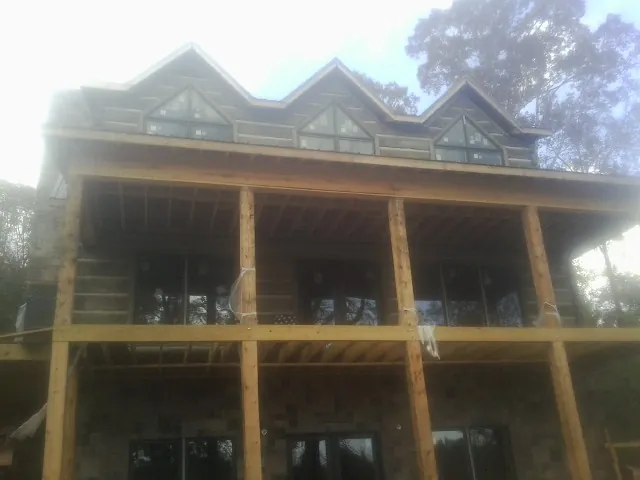 Dormers and porch framing on a large log home under construction — Roof Coating work by our crew in Gates Mills