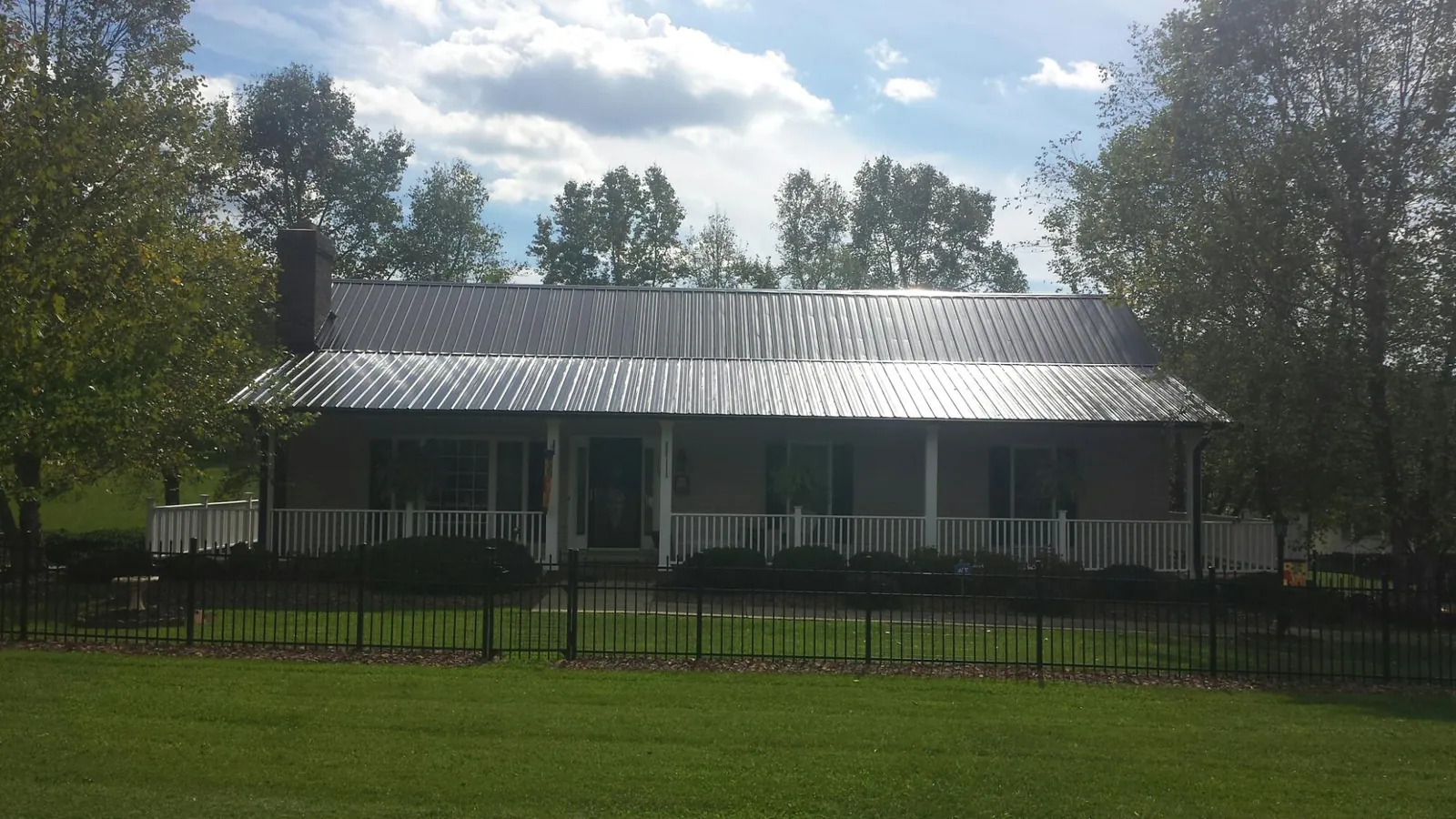 Gray metal roof on a brick ranch with a full width front porch — Gutter Guard Installation work by our crew in Gates Mills