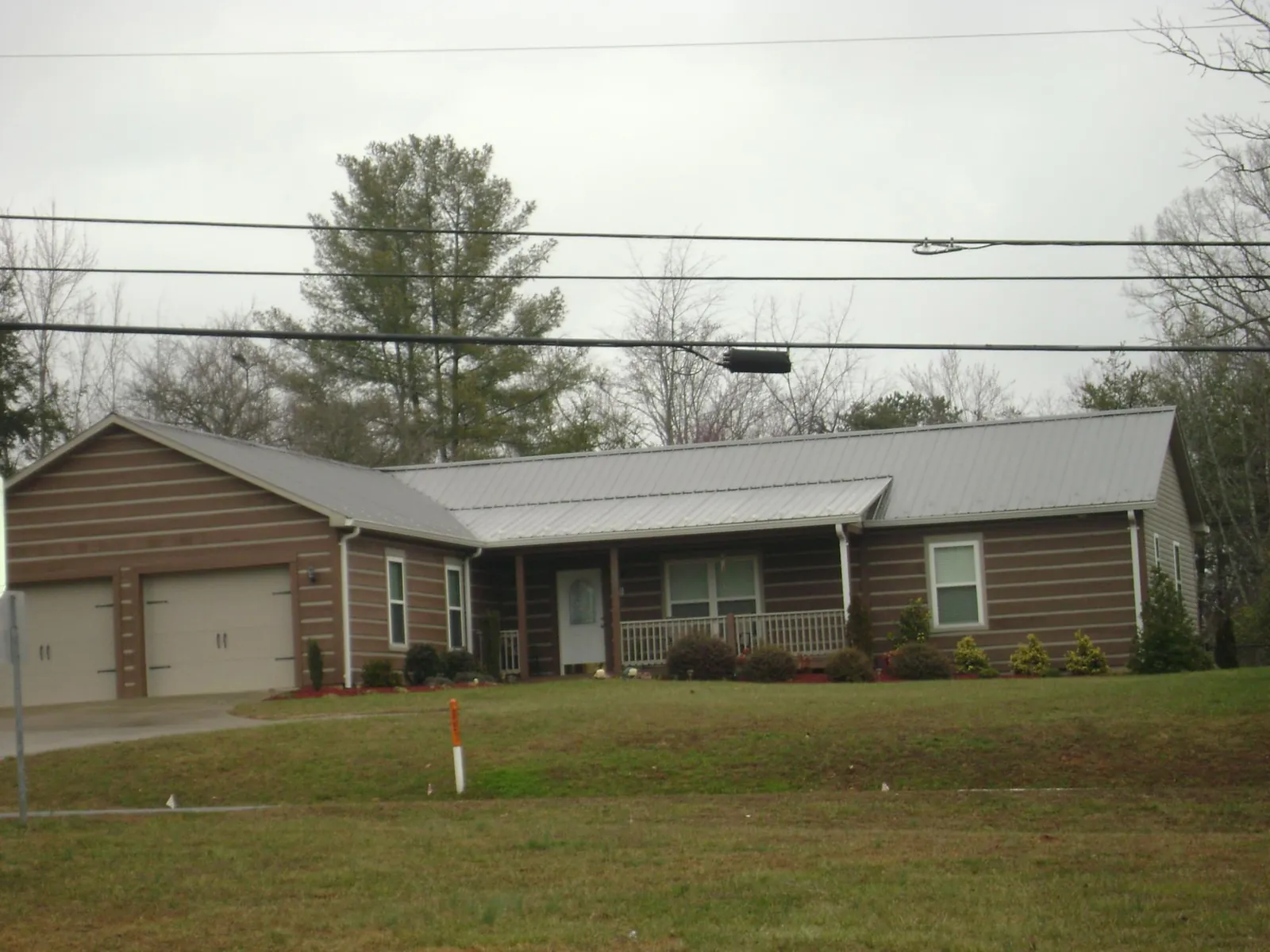 Gray metal roof on a log sided ranch home with a front porch in Gates Mills