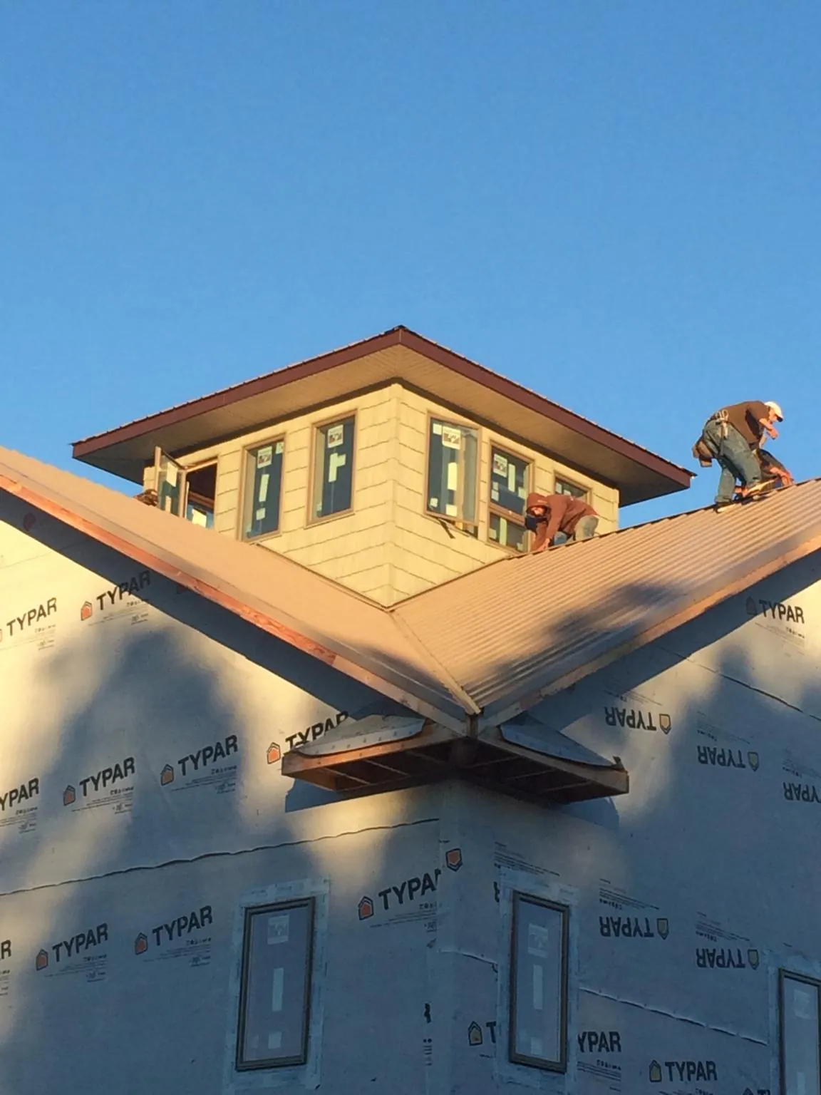 Roofers working around a rooftop cupola on a new metal roof at sunset — Roof Waterproofing in Gates Mills by Roofing Brothers